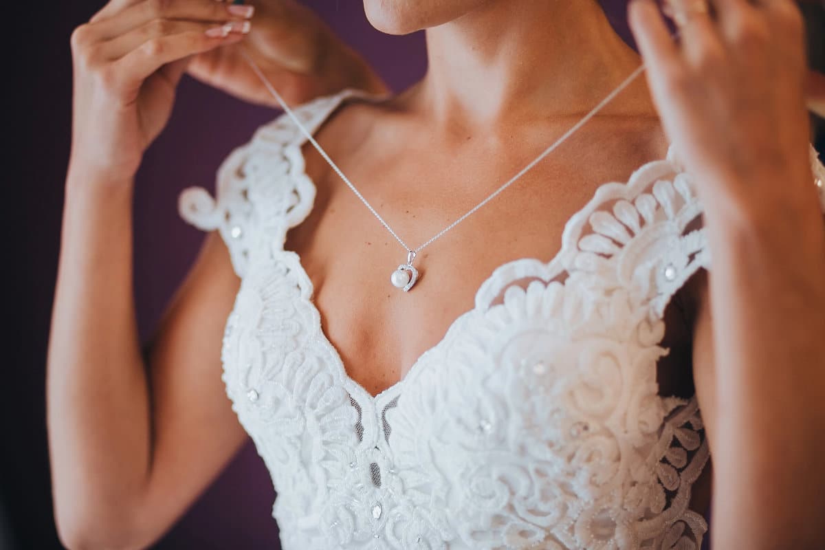 Une mariée en train de mettre un joli collier